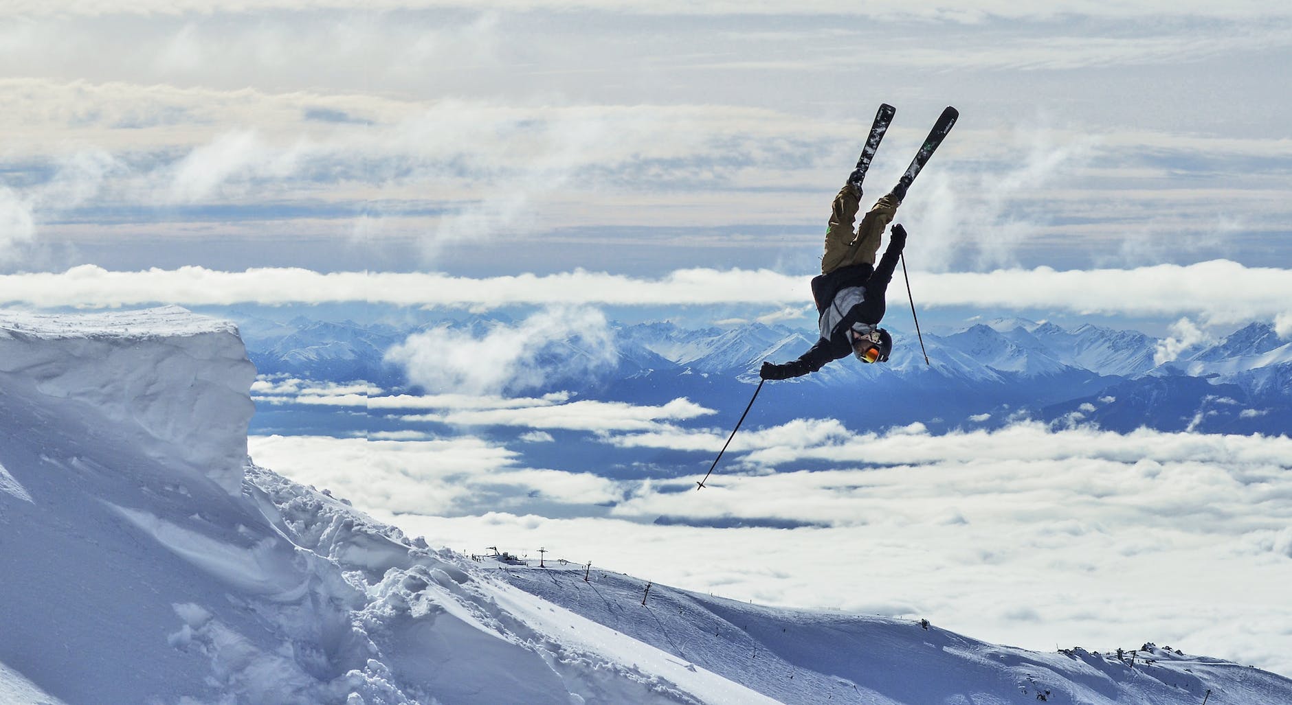 unrecognizable skier performing upside down trick in snowy mountains